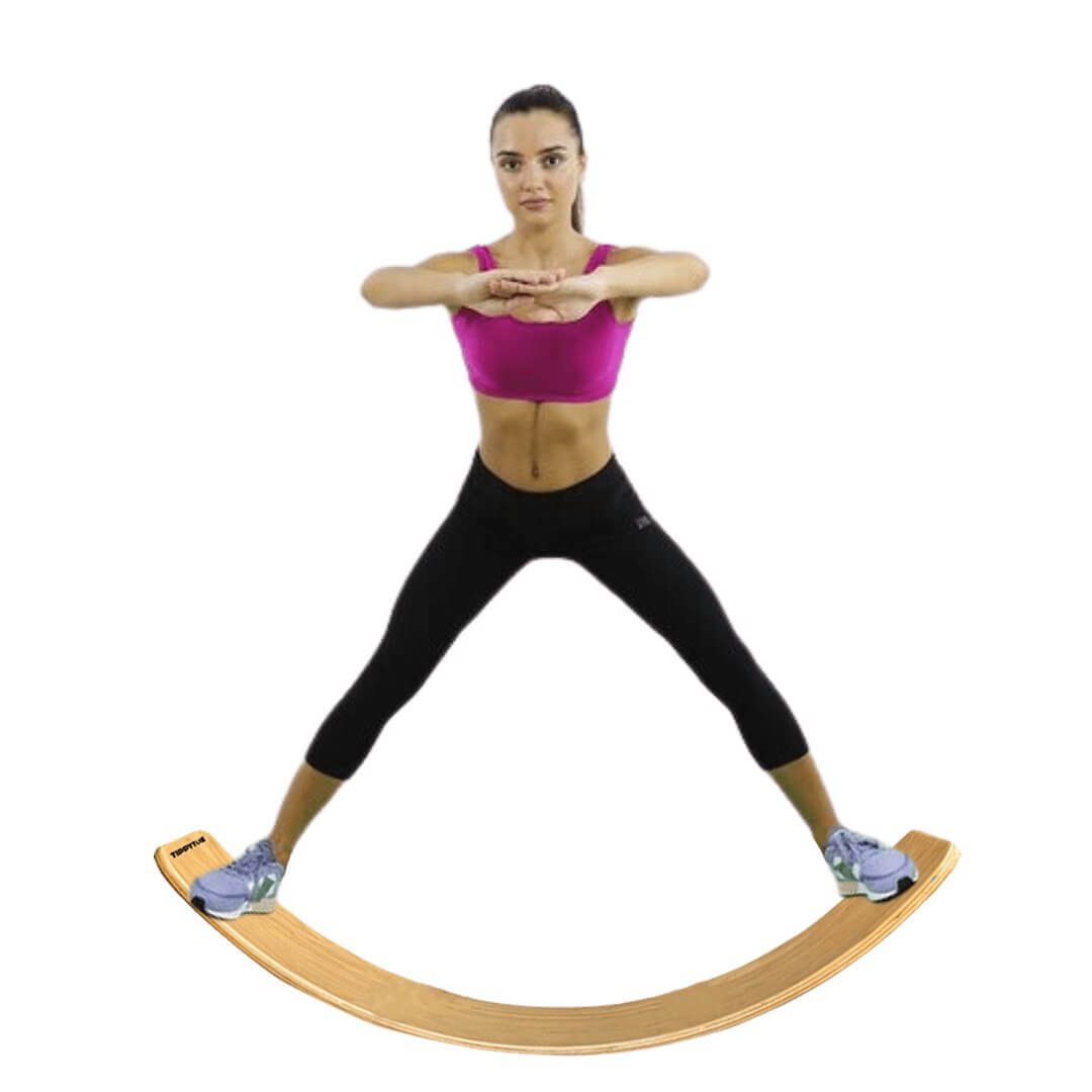 Woman balancing on BILLY Wooden Balance Board, wearing exercise attire, showcasing balance and stability on natural wood wobble board.